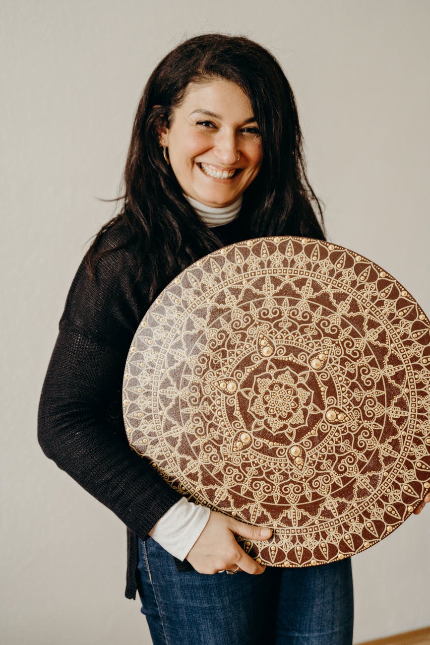 woman in black sweater holding a brown and beige mandala